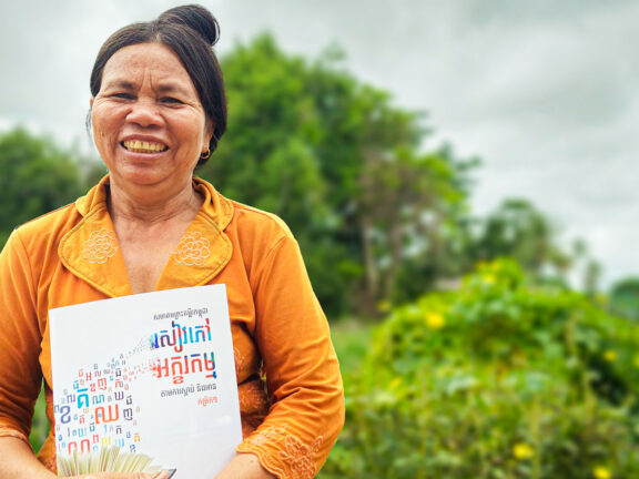 Kim is holding her literacy textbook with a big smile on her face, full of hope, and confidence.